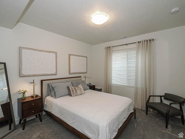 bedroom with dark carpet, multiple windows, and a textured ceiling