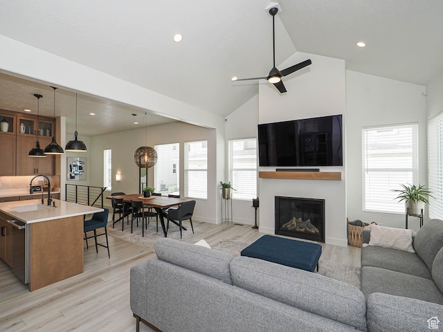 living room featuring a glass covered fireplace, light wood-type flooring, recessed lighting, healthy amount of natural light, and a ceiling fan