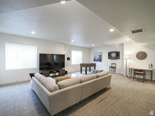 carpeted living area featuring baseboards, a textured ceiling, and recessed lighting