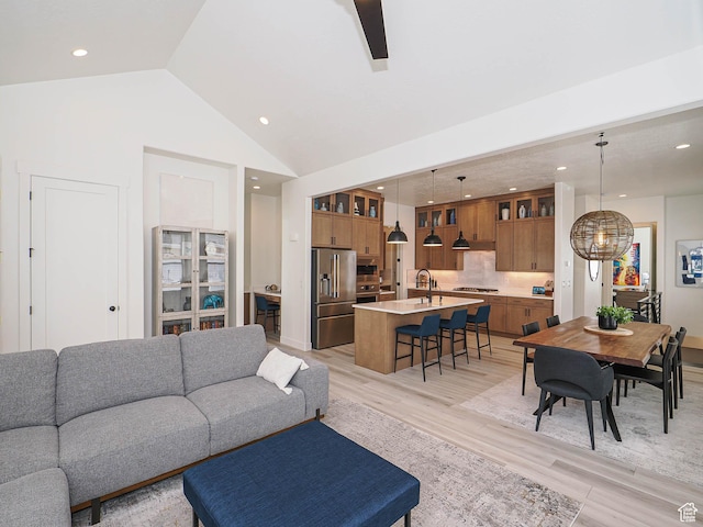 living area with light wood-style flooring, recessed lighting, vaulted ceiling, ceiling fan, and a chandelier