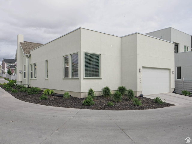 view of side of property with a garage, concrete driveway, and stucco siding
