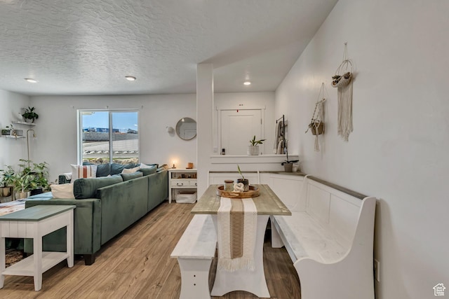 dining area with light wood-style floors, a textured ceiling, and recessed lighting