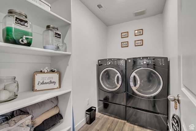 clothes washing area featuring washer and dryer and wood finished floors
