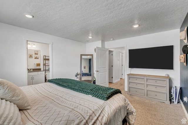 carpeted bedroom with ensuite bath, a textured ceiling, recessed lighting, and baseboards