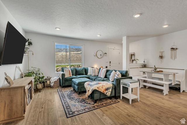 living room featuring a textured ceiling, light wood-type flooring, and recessed lighting