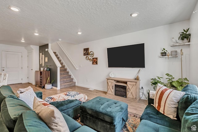 living area featuring stairway, a textured ceiling, wood finished floors, recessed lighting, and baseboards
