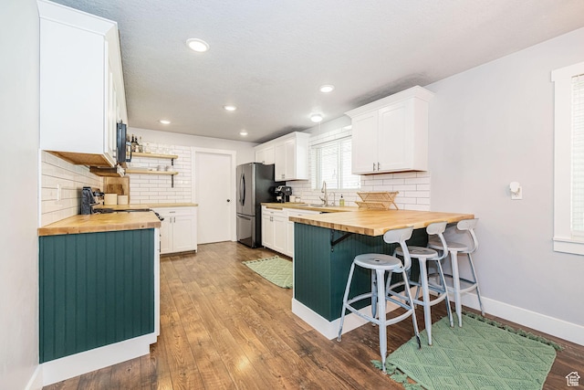 4302 W 2350 N, Plain City, UT 84404 - kitchen with butcher block counters, freestanding refrigerator, a breakfast bar, backsplash, and recessed lighting