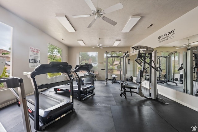 workout area with a ceiling fan, a textured ceiling, and baseboards