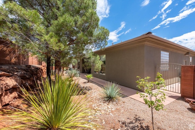 view of side of home with a gate and stucco siding