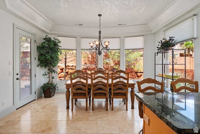 dining room with a chandelier, plenty of natural light, a raised ceiling, and stone tile flooring