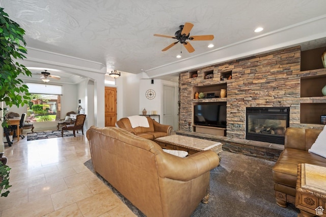 living room with a ceiling fan, arched walkways, a stone fireplace, recessed lighting, and tile patterned flooring