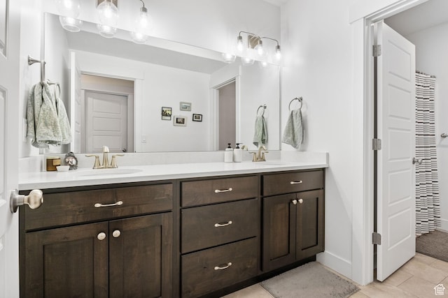bathroom featuring double vanity, tile patterned floors, and baseboards