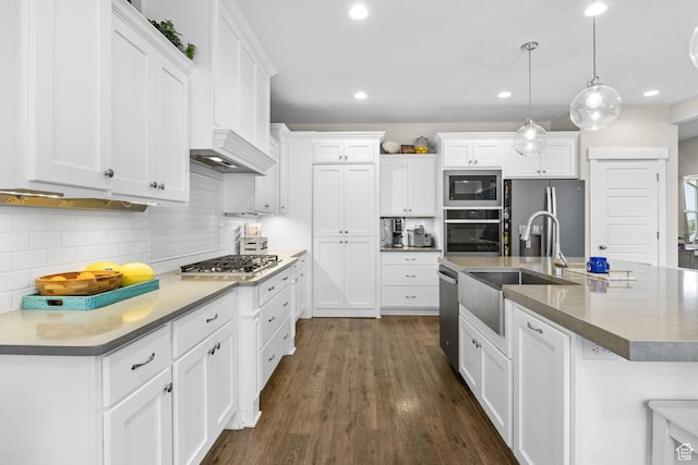 kitchen with appliances with stainless steel finishes, a sink, white cabinets, tasteful backsplash, and recessed lighting