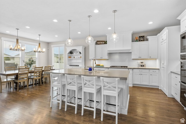 kitchen featuring a sink, appliances with stainless steel finishes, decorative backsplash, a kitchen breakfast bar, and a kitchen island with sink