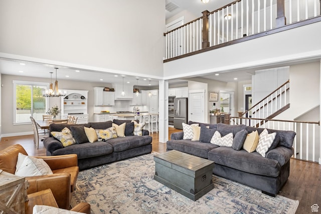 living area featuring wood finished floors, a chandelier, a high ceiling, baseboards, and recessed lighting