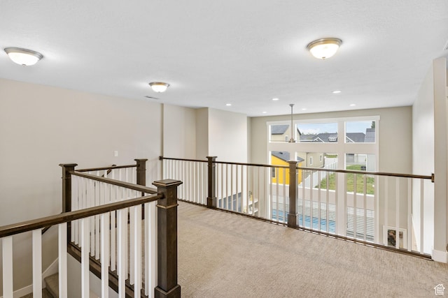 corridor with carpet floors and an upstairs landing