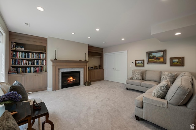 living room featuring recessed lighting, carpet flooring, a fireplace, and built in shelves