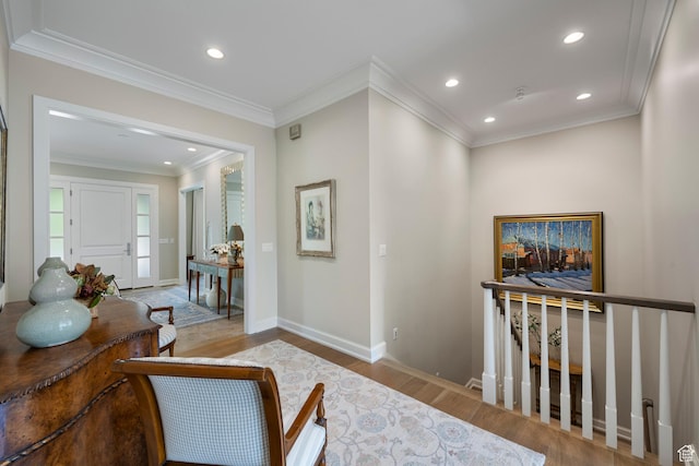 hallway featuring wood finished floors, baseboards, recessed lighting, crown molding, and an upstairs landing