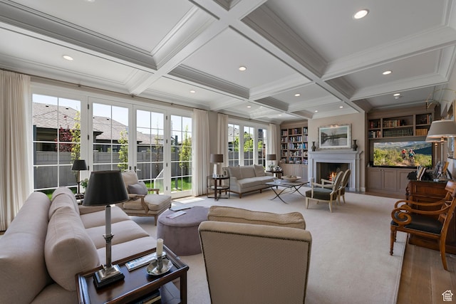 living area featuring beamed ceiling, coffered ceiling, a lit fireplace, ornamental molding, and built in shelves