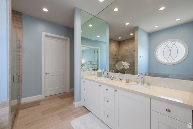 full bathroom with a shower stall, wood finished floors, recessed lighting, double vanity, and baseboards