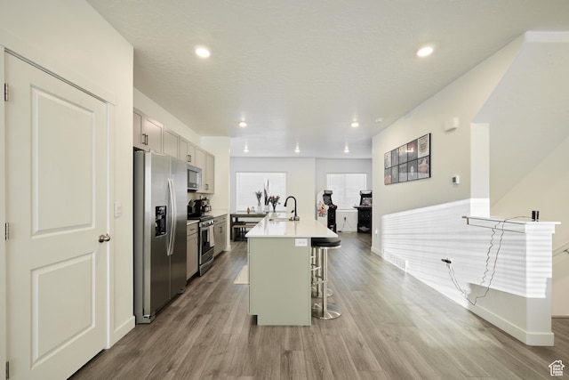 311 S 1130 W Unit 24, American Fork, UT 84003 - kitchen featuring stainless steel appliances, a breakfast bar, a kitchen island with sink, wood finished floors, and light countertops