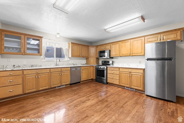 1688 N 175 W, Cedar City, UT 84721 - kitchen with stainless steel appliances, a textured ceiling, light wood-type flooring, glass insert cabinets, and a sink