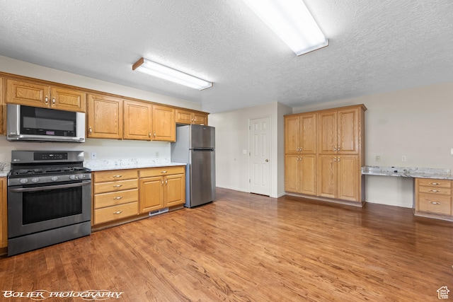 1688 N 175 W, Cedar City, UT 84721 - kitchen with stainless steel appliances, a textured ceiling, wood finished floors, and brown cabinets