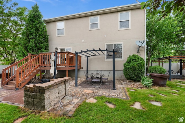 rear view of house featuring a pergola, a deck, a lawn, a patio area, and stucco siding
