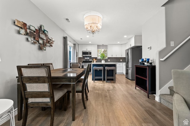 dining area featuring a chandelier, light wood finished floors, stairs, recessed lighting, and baseboards