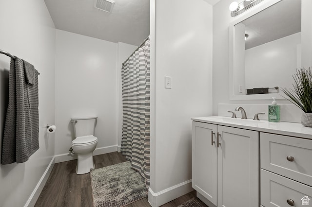 bathroom with wood finished floors, toilet, vanity, and baseboards