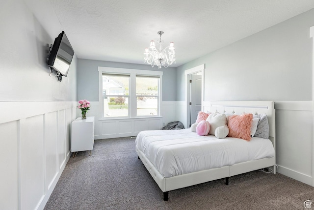 bedroom with a chandelier, carpet flooring, wainscoting, and a decorative wall