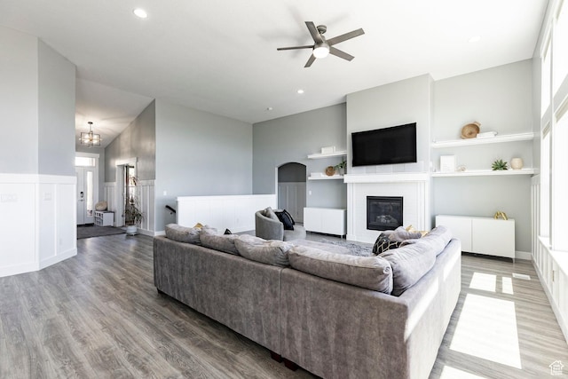 living room featuring ceiling fan, a glass covered fireplace, built in shelves, light wood finished floors, and healthy amount of natural light