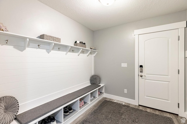 mudroom with dark wood finished floors, a textured ceiling, and baseboards