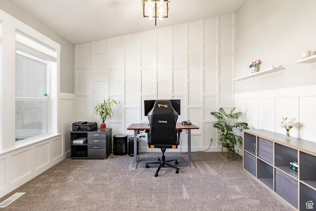 carpeted office space with a decorative wall, wainscoting, and lofted ceiling