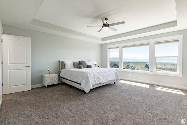 bedroom with a tray ceiling, carpet floors, baseboards, and ceiling fan