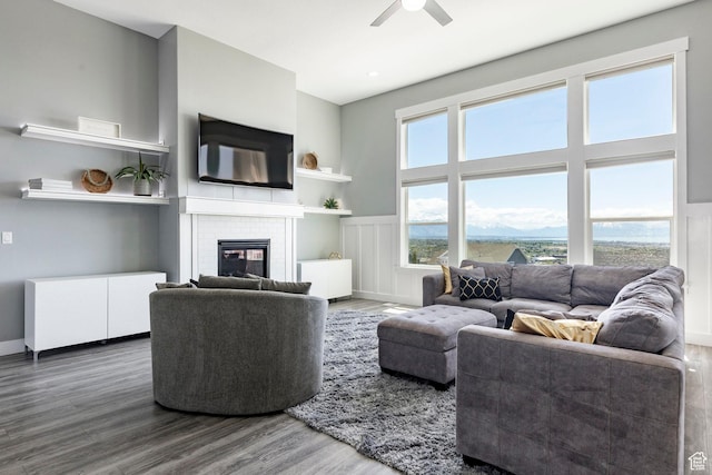 living area with wood finished floors, a ceiling fan, and a brick fireplace