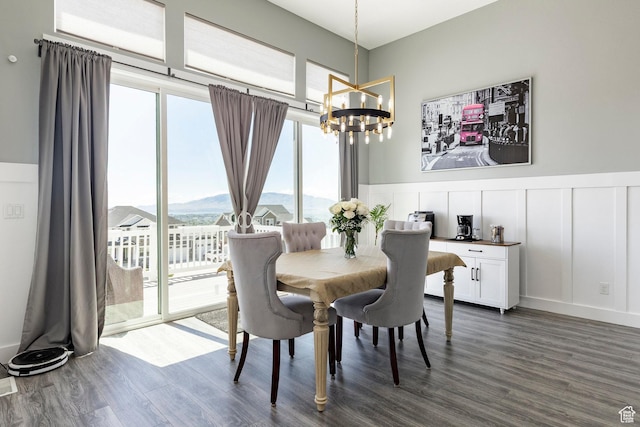 dining room with a chandelier, dark wood-style floors, a decorative wall, a wainscoted wall, and a mountain view