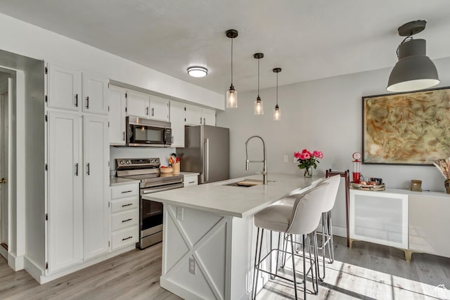 kitchen featuring appliances with stainless steel finishes, a sink, light wood-style floors, and white cabinets