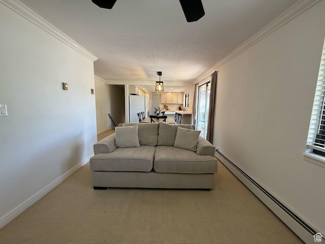 living area featuring a baseboard heating unit, light colored carpet, baseboards, ornamental molding, and a ceiling fan