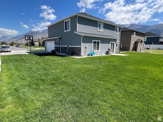1297 W 450 N, Springville, UT 84663 - back of house featuring a mountain view, stucco siding, stone siding, an attached garage, and a yard