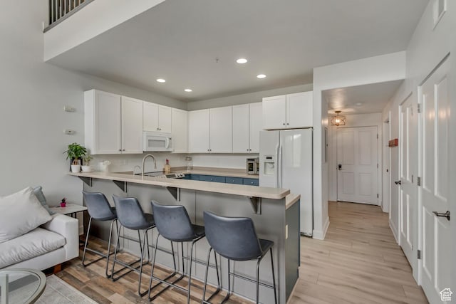 6641 N 2200 W Unit D-304, Park City, UT 84098 - kitchen with white appliances, a kitchen bar, a peninsula, recessed lighting, and white cabinetry