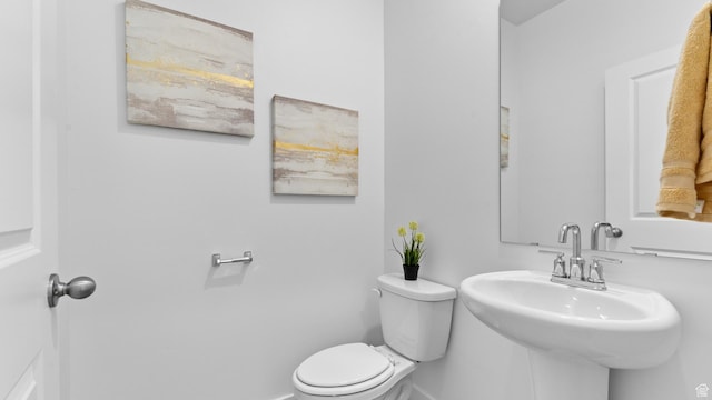 half bath featuring baseboards, a sink, and toilet