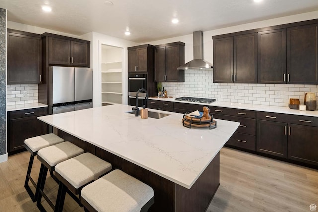 1513 E 820 N Unit 105, Salem, UT 84653 - kitchen featuring wall chimney range hood, a sink, appliances with stainless steel finishes, a kitchen bar, and light wood finished floors