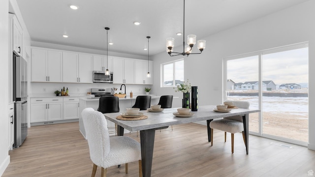 dining room with light wood finished floors, a chandelier, and recessed lighting