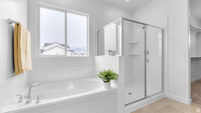 bathroom with a stall shower, a bath, a walk in closet, and tile patterned floors