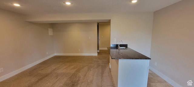 empty room with recessed lighting, a sink, light carpet, and baseboards