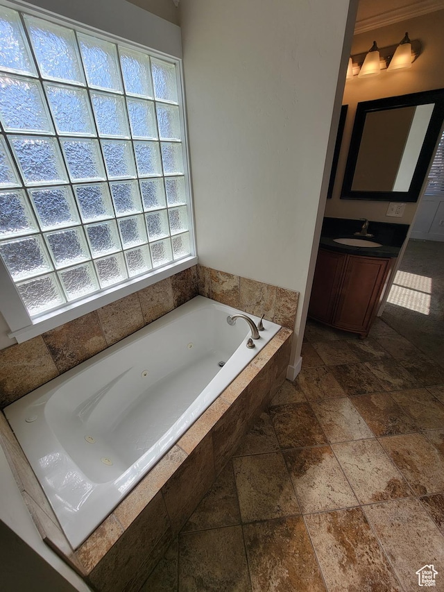 full bath featuring stone tile flooring, a jetted tub, and vanity