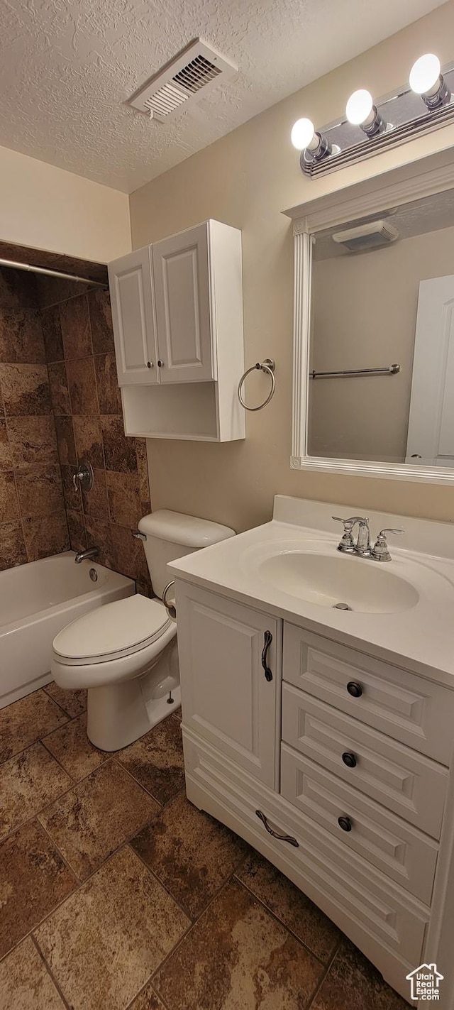 full bathroom with toilet, vanity, a textured ceiling, stone tile flooring, and shower / bathtub combination