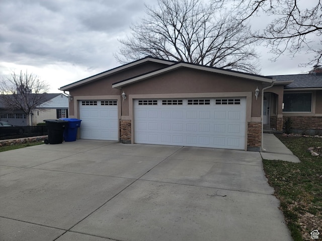 single story home featuring stone siding, a garage, driveway, and stucco siding