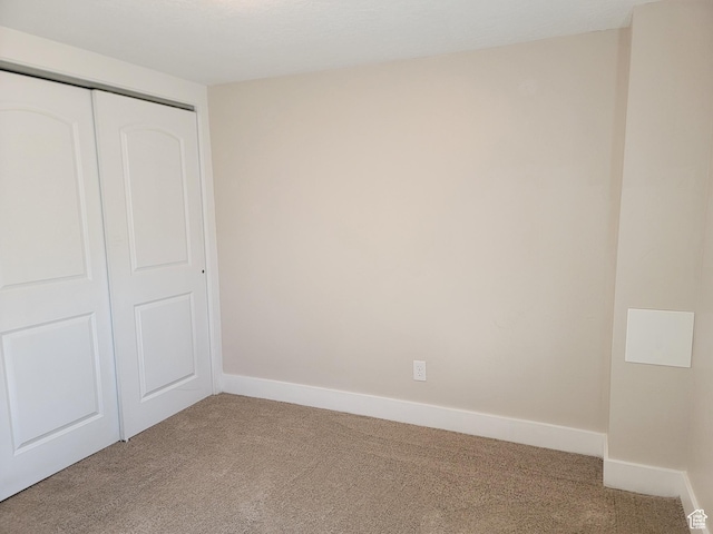 unfurnished bedroom with carpet flooring, a closet, and baseboards